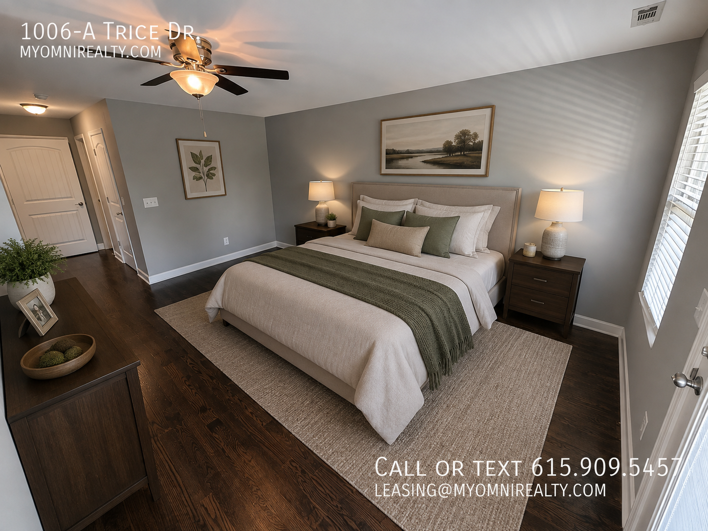 Staged bedroom in a rental home with a large bed, two nightstands, and matching lamps on either side, neutral decor, and a ceiling fan.