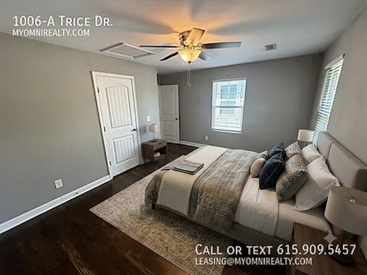 Bedroom in a modern rental: queen bed with neutral bedding, two nightstands, ceiling fan, and two windows; contact 615-909-5457 for leasing (1006-A Trice Dr., myomni Realty).